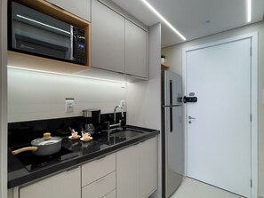 A modern kitchen with a built-in microwave, a coffee maker, and a refrigerator. - Lasar Chácara Klabin (São Paulo)