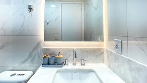 Un baño moderno con lavamanos de mármol, un espejo y un inodoro.