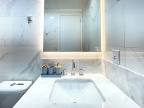 A modern bathroom with a marble sink, a mirror, and a toilet. - Lasar Chácara Klabin (São Paulo)