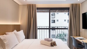 Una habitación de hotel con una cama, un escritorio y vista a la ciudad.