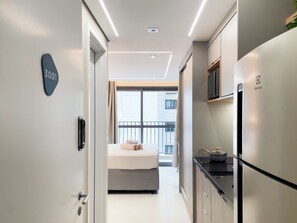 A modern hotel room with a bed, a kitchenette, and a balcony. - Lasar Chácara Klabin (São Paulo)