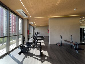 A gym with exercise equipment, large windows, and a wooden ceiling. - Lasar Chácara Klabin (S ão Paulo)
