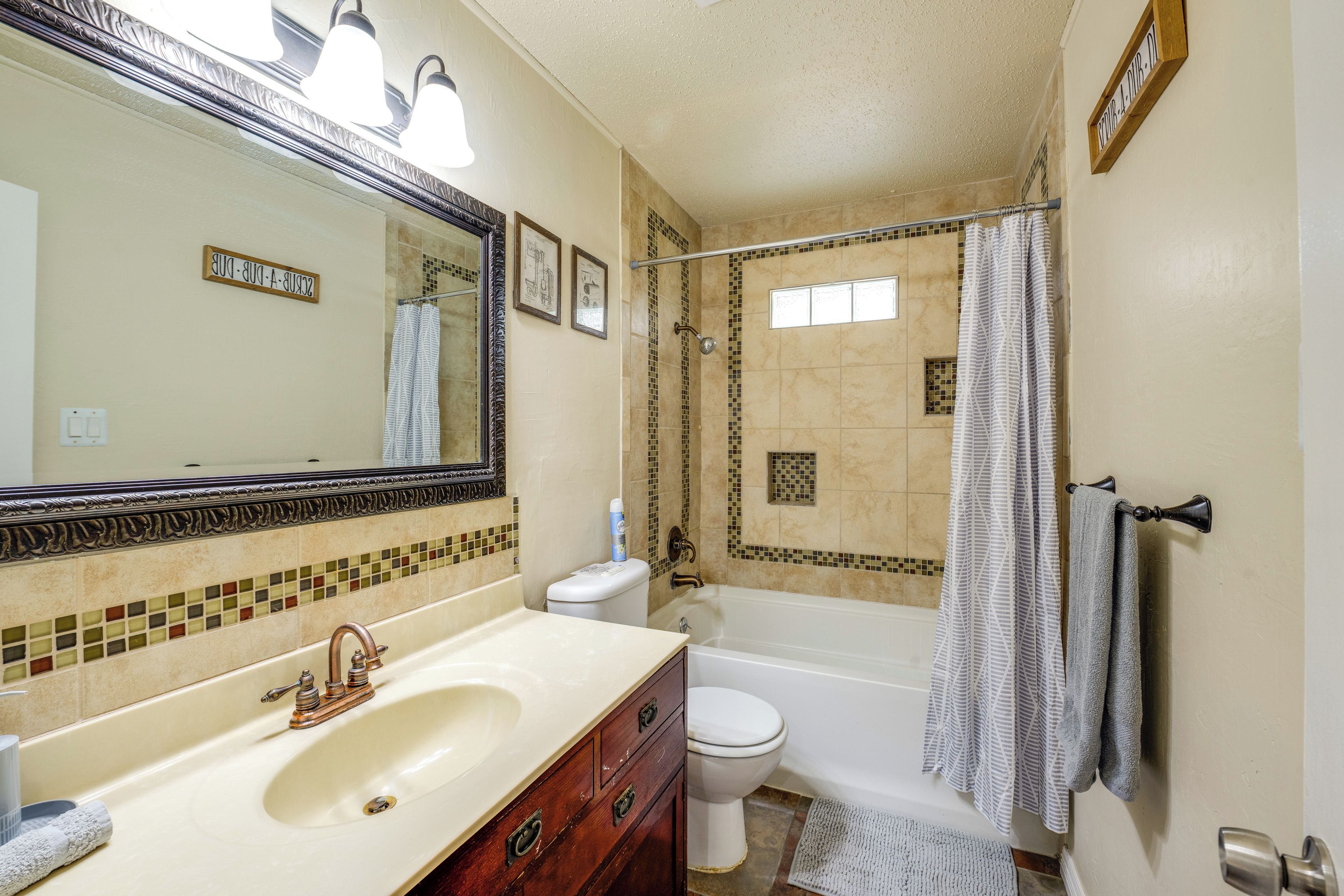 Un baño con bañera, inodoro y un espejo grande.