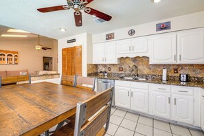A kitchen with white cabinets, a granite countertop, and a wooden dining table. - Family-friendly Home w/ Hot Tub in San Antonio! (San Antonio)