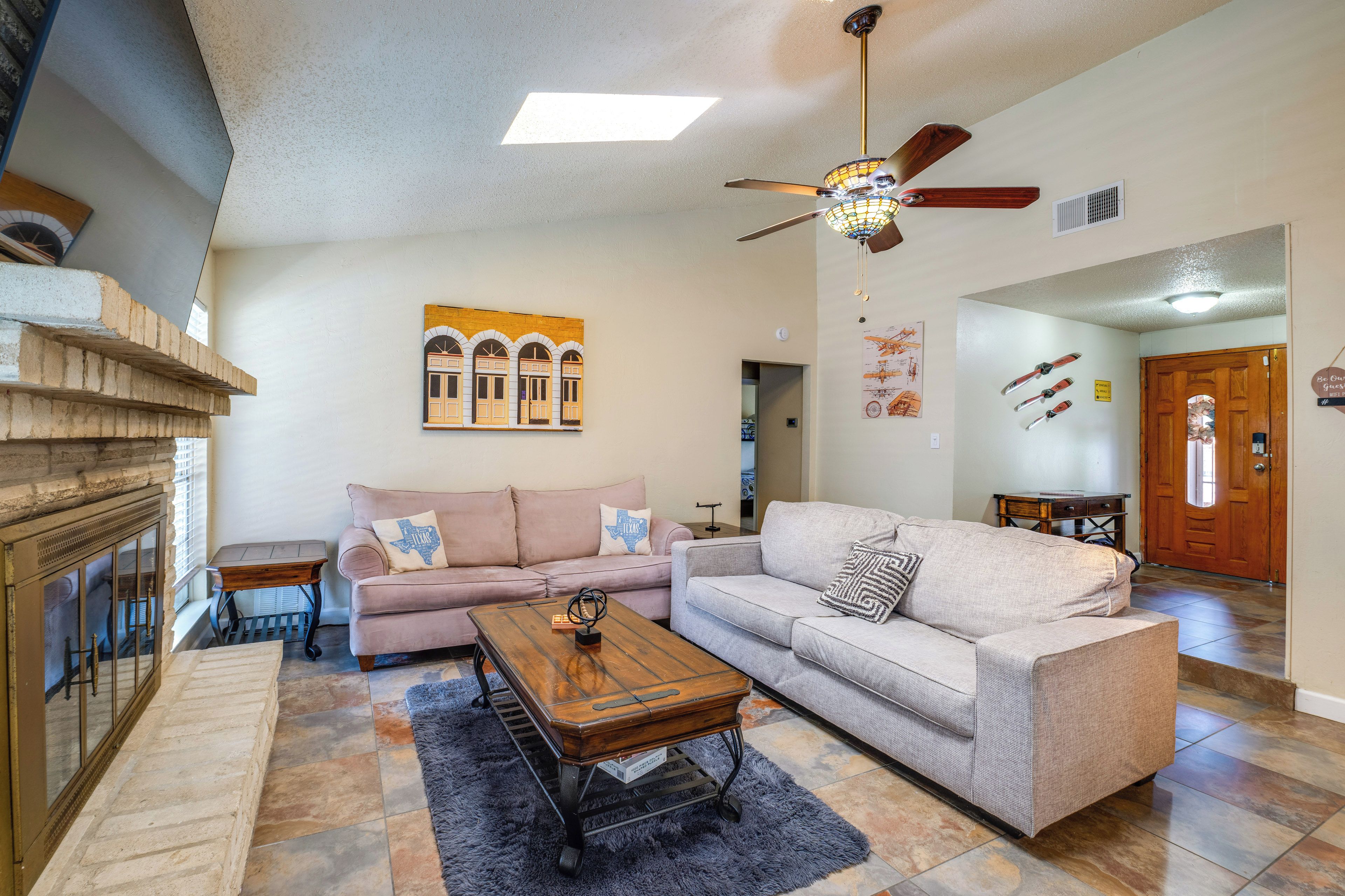 A living room with a fireplace, two sofas, a coffee table, and a ceiling fan.