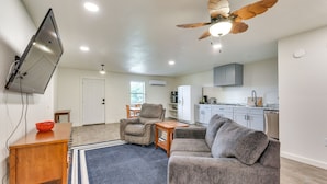A modern living room with a flat-screen TV, a ceiling fan, and a kitchen area with cabinets and appliances. - 2 Red Level Rentals on a Working Farm! (Red Level)