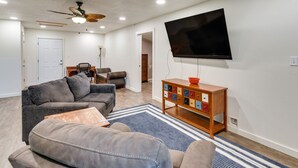 A living room with a grey sectional sofa, a wooden coffee table, a flat-screen TV, and a ceiling fan. - 2 Red Level Rentals on a Working Farm! (Red Level)