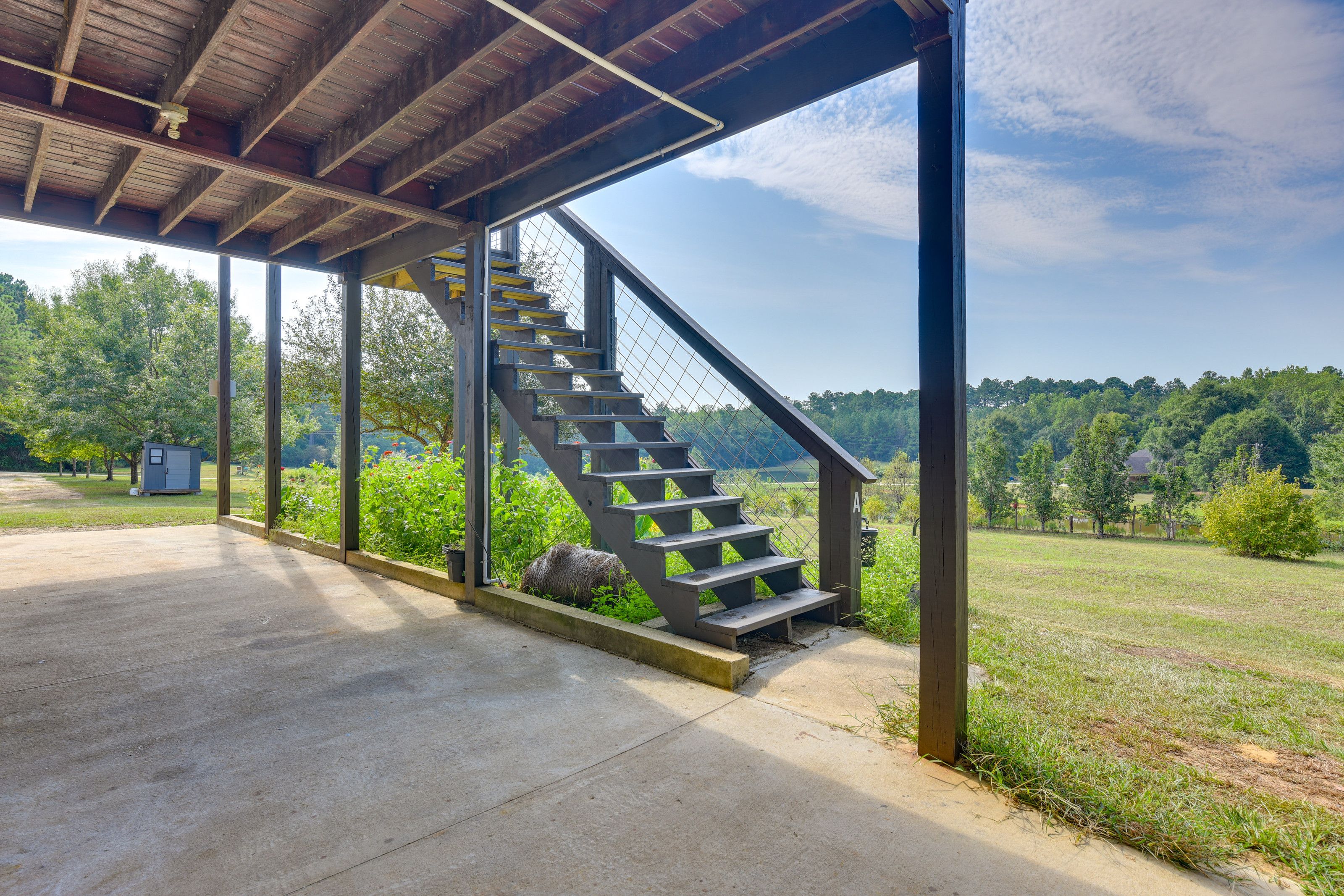 A covered outdoor staircase leading to a grassy area with a view of trees and a clear sky.