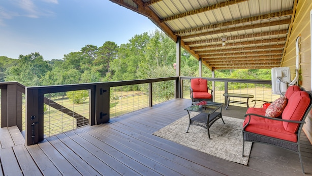 A covered outdoor deck with a view of a forest, a table, and two chairs. - 2 Red Level Rentals on a Working Farm! (Red Level)