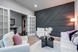A modern living room with white furniture, a dark accent wall, and a coffee table with decorative items.