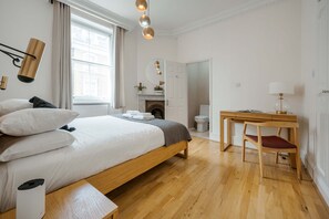 A modern bedroom with a wooden bed, bedside table, and a desk with a chair. - South Kensington 2-bed - Lift - Sleeps 6 (London)