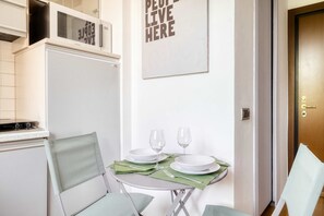 A compact kitchen with a microwave, a Samsung oven, and a dining area with a table set for two. - w Bright Apartment 1BR in the Heart of Isola (Milan)