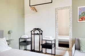 A hotel room with a bed, a desk with a chair, a mirror, and a towel rack. - w Bright Apartment 1BR in the Heart of Isola (Milan)