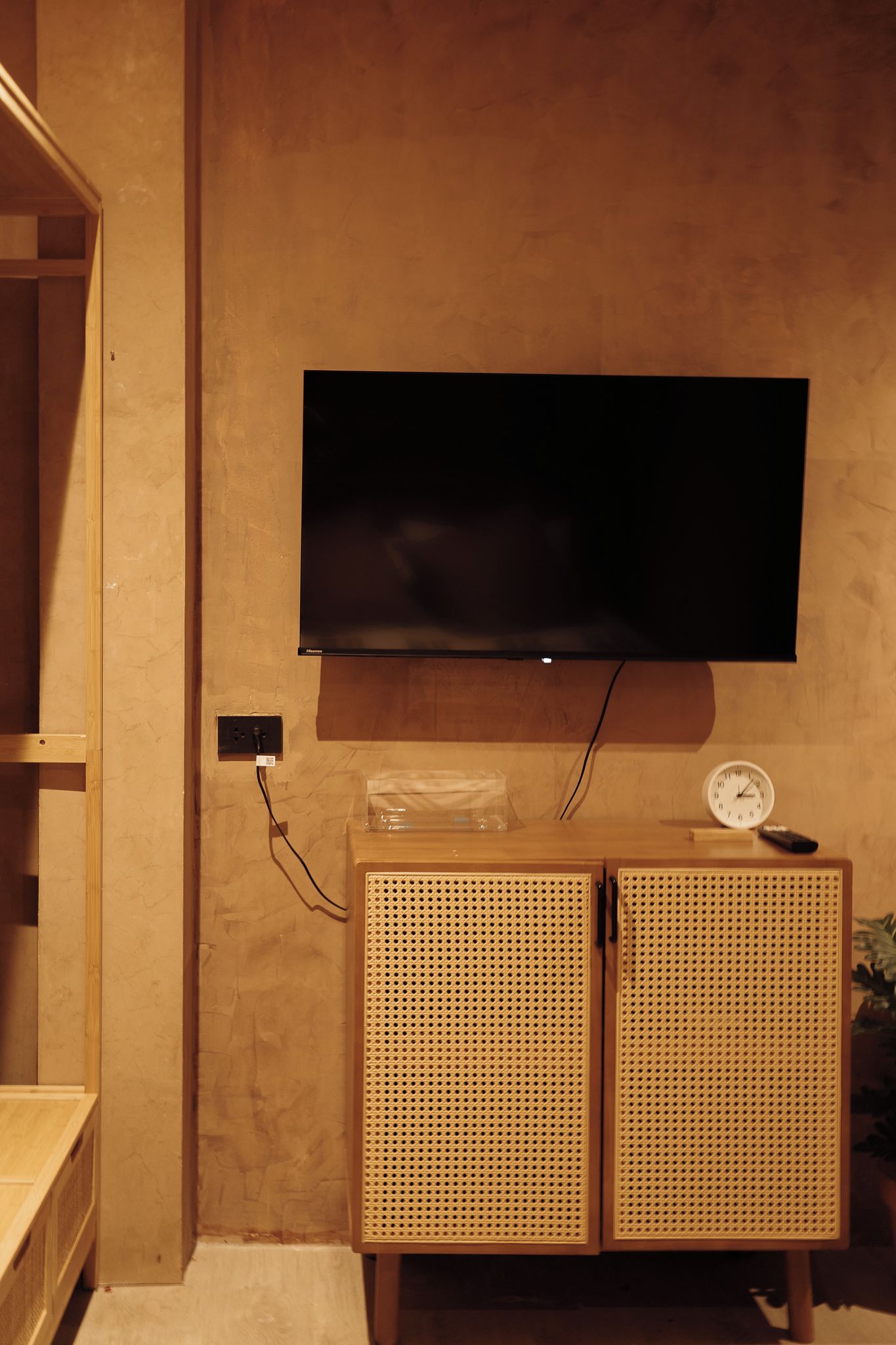 A television mounted on a wall with a wooden cabinet below.