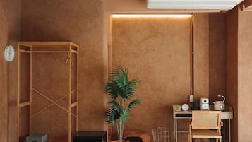 Una habitación con un armario de madera, una planta en maceta, un escritorio con una silla, una mesita, un reloj y un aire acondicionado.