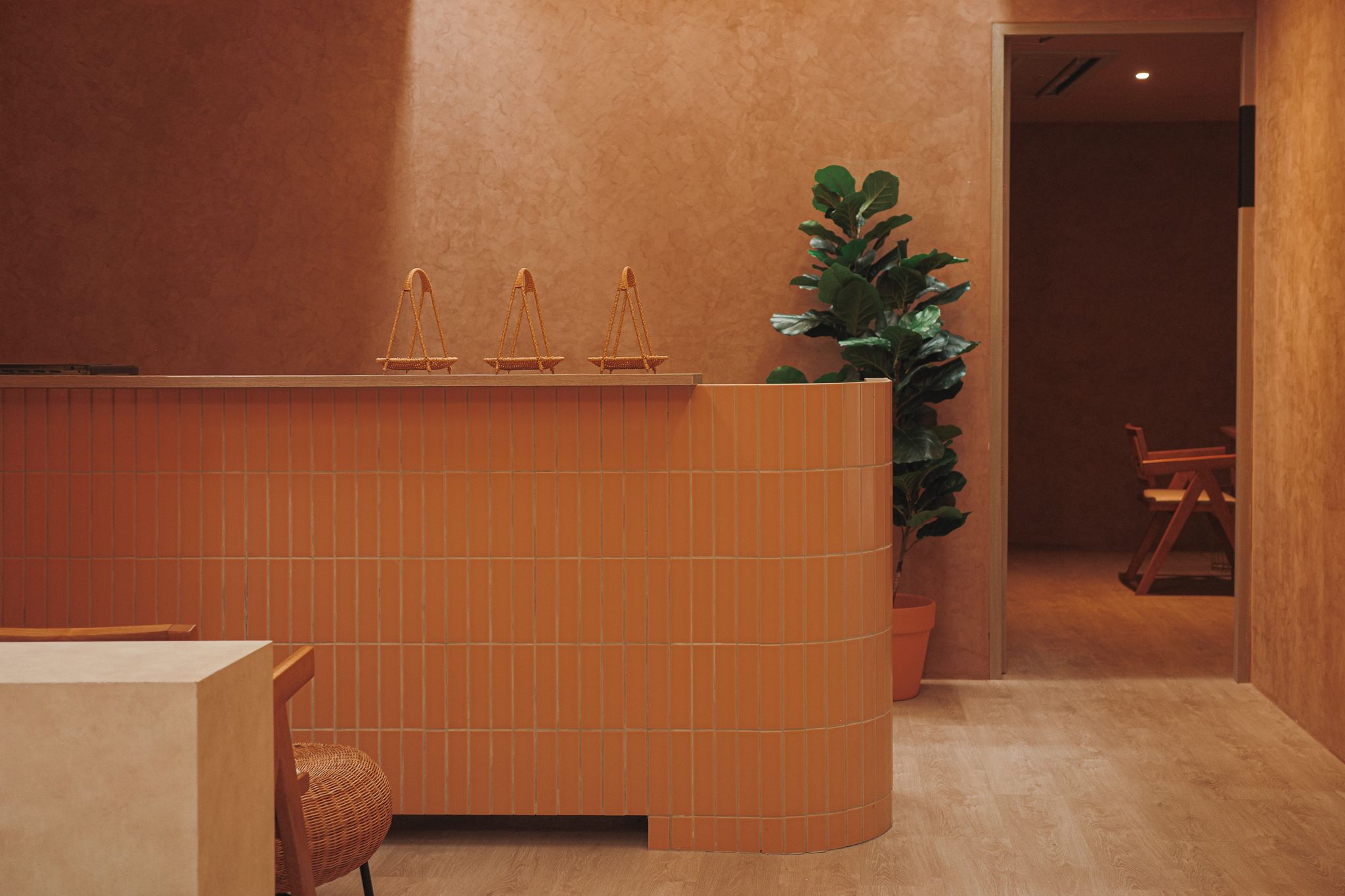 A reception area with a tiled counter, a potted plant, and a wooden chair.