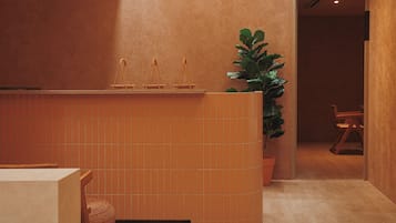 A reception area with a tiled counter, a potted plant, and a wooden chair.