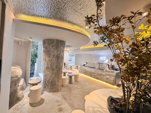 A modern interior with a reception desk, seating areas, and a large stone column. - Apt. CAI 04 Aparthotel (Krung Thep Maha Nakhon)