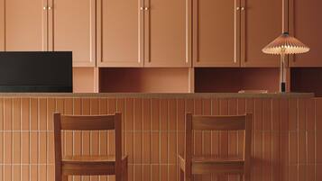 Een keuken met houten kastjes, een zwart aanrecht en twee houten stoelen.