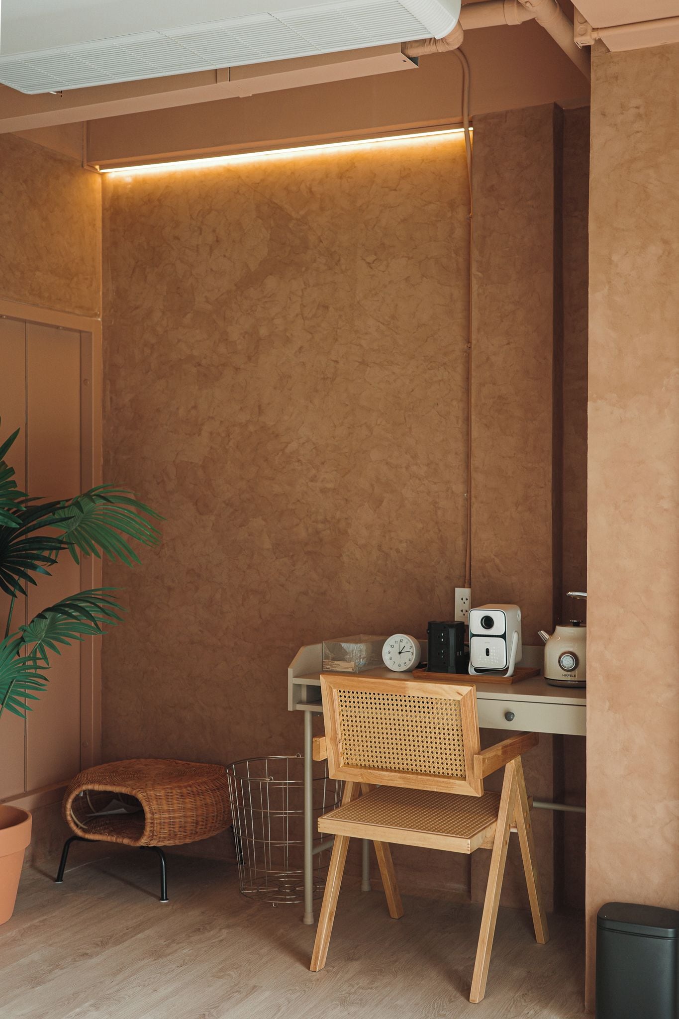 A corner room with a desk, chair, and a plant.