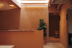 A restaurant interior with a tiled counter, a potted plant, and a view of the dining area. - Apt. CAI 04 Aparthotel (Krung Thep Maha Nakhon)