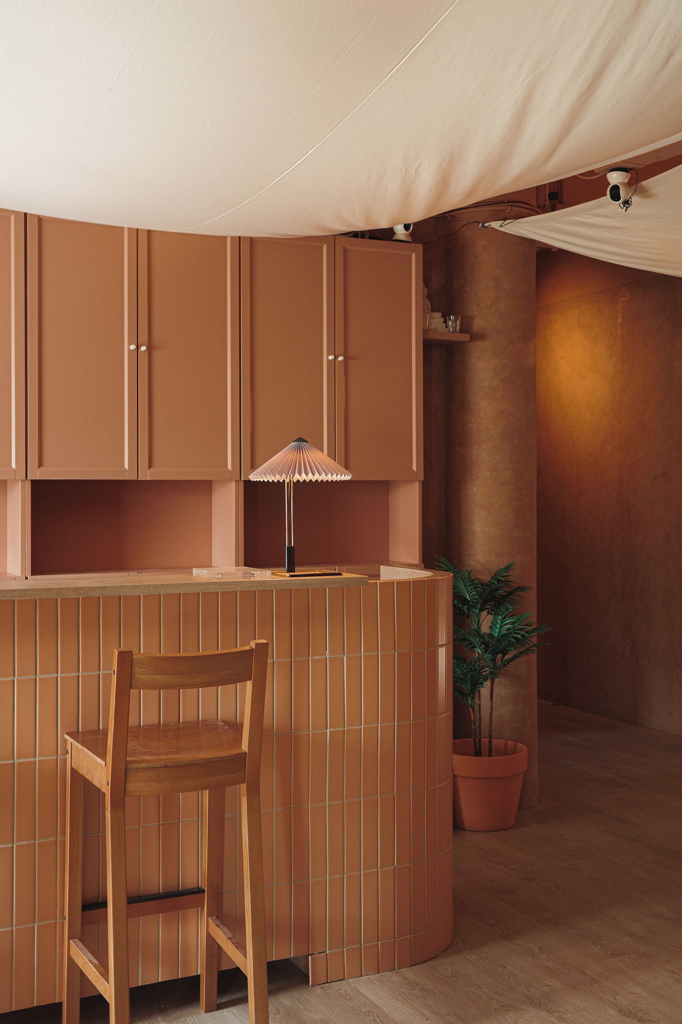 Une pièce comprenant un coin bar en bois, une chaise, une plante en pot et une structure ressemblant à une tente.