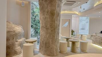 Un interior moderno con una columna central imponente, varias zonas de estar y vistas a la vegetación.