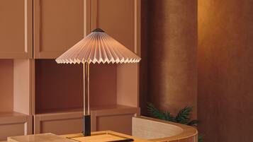 Een kamer met een houten kast, een tafel met een lamp en een plant.