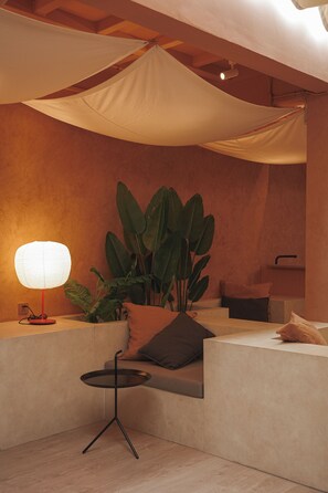 A modern interior with a seating area, a lamp, and large plants.