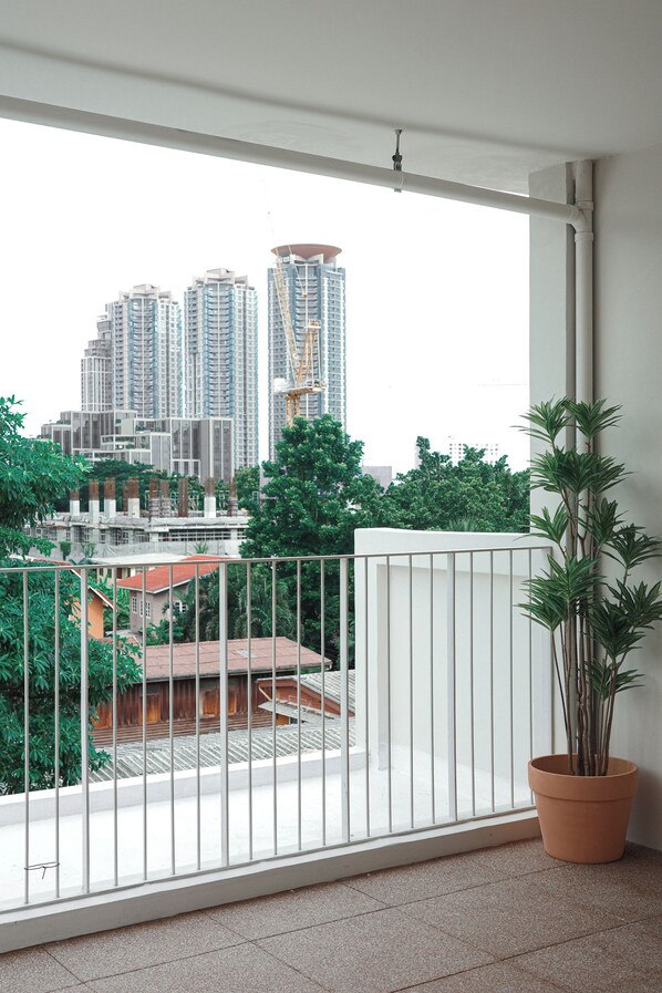 A balcony with a view of high-rise buildings and a potted plant.