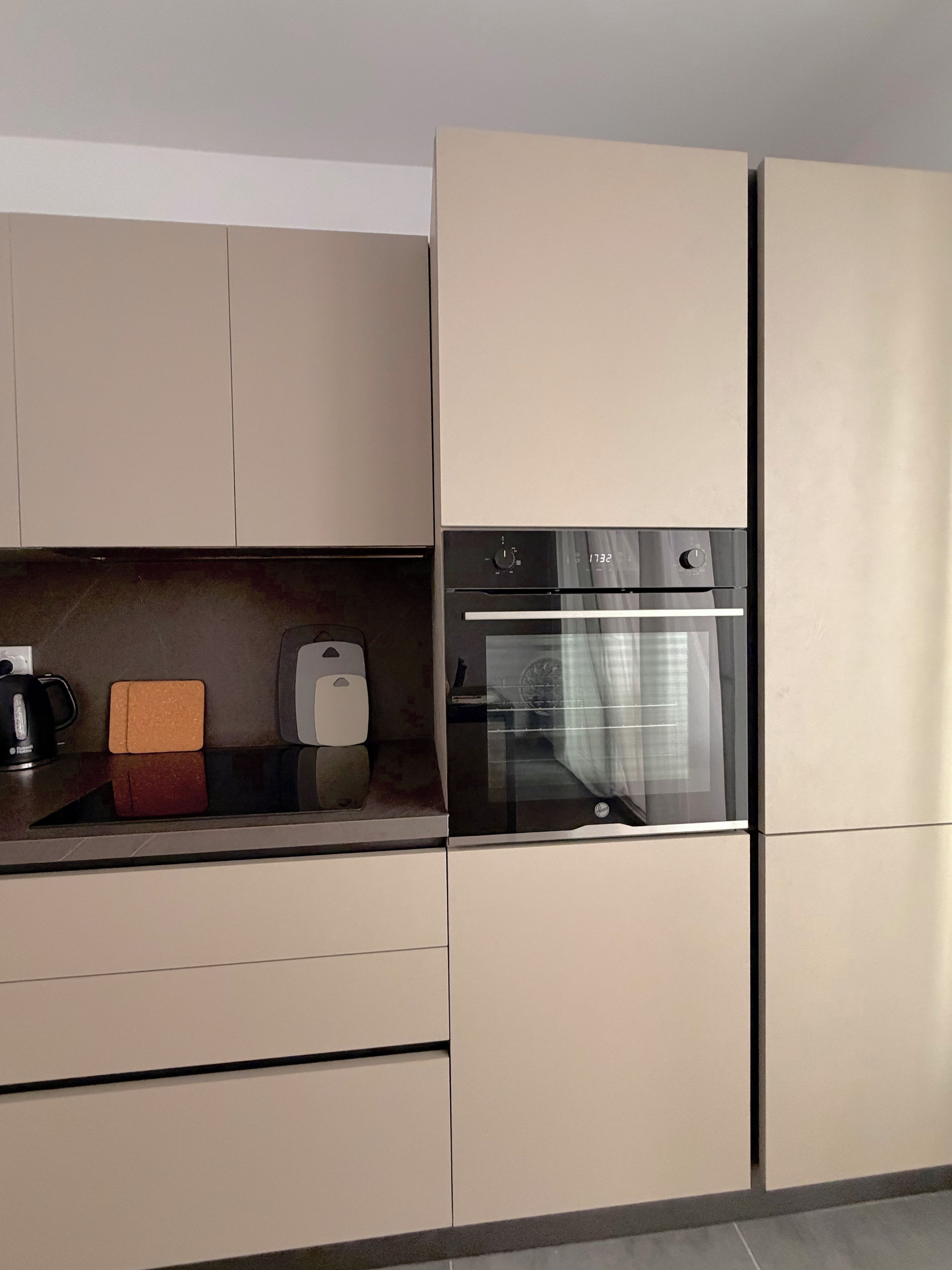 A modern kitchen with a built-in oven and a coffee maker on the counter.