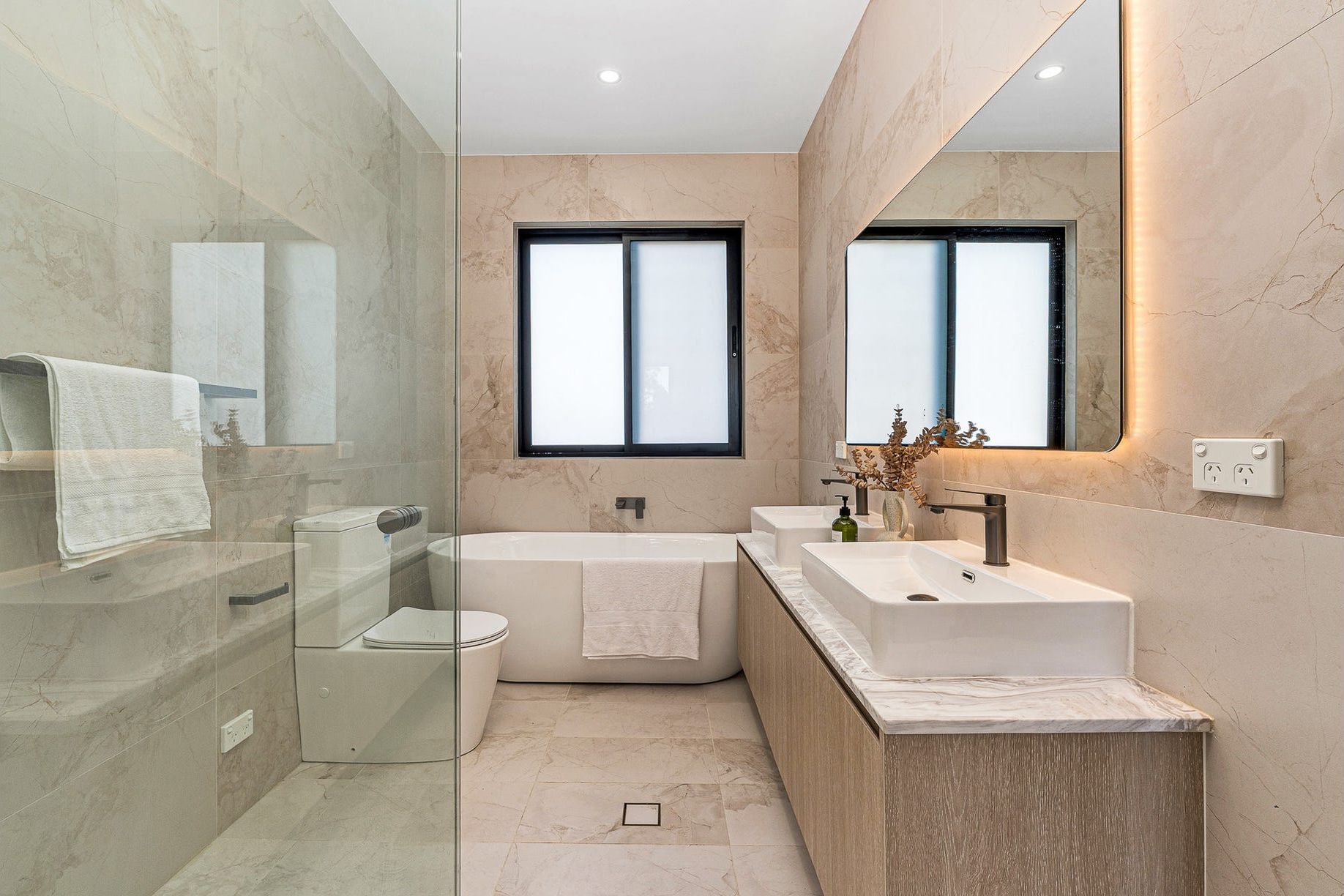 A modern bathroom with a glass shower enclosure, a freestanding bathtub, and a vanity with a sink.