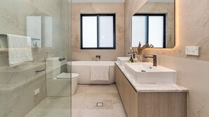 Een moderne badkamer met een douchecabine van glas, een vrijstaand bad en een wastafelmeubel met een wastafel.
