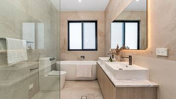 A modern bathroom with a glass shower enclosure, a freestanding bathtub, and a vanity with a sink.