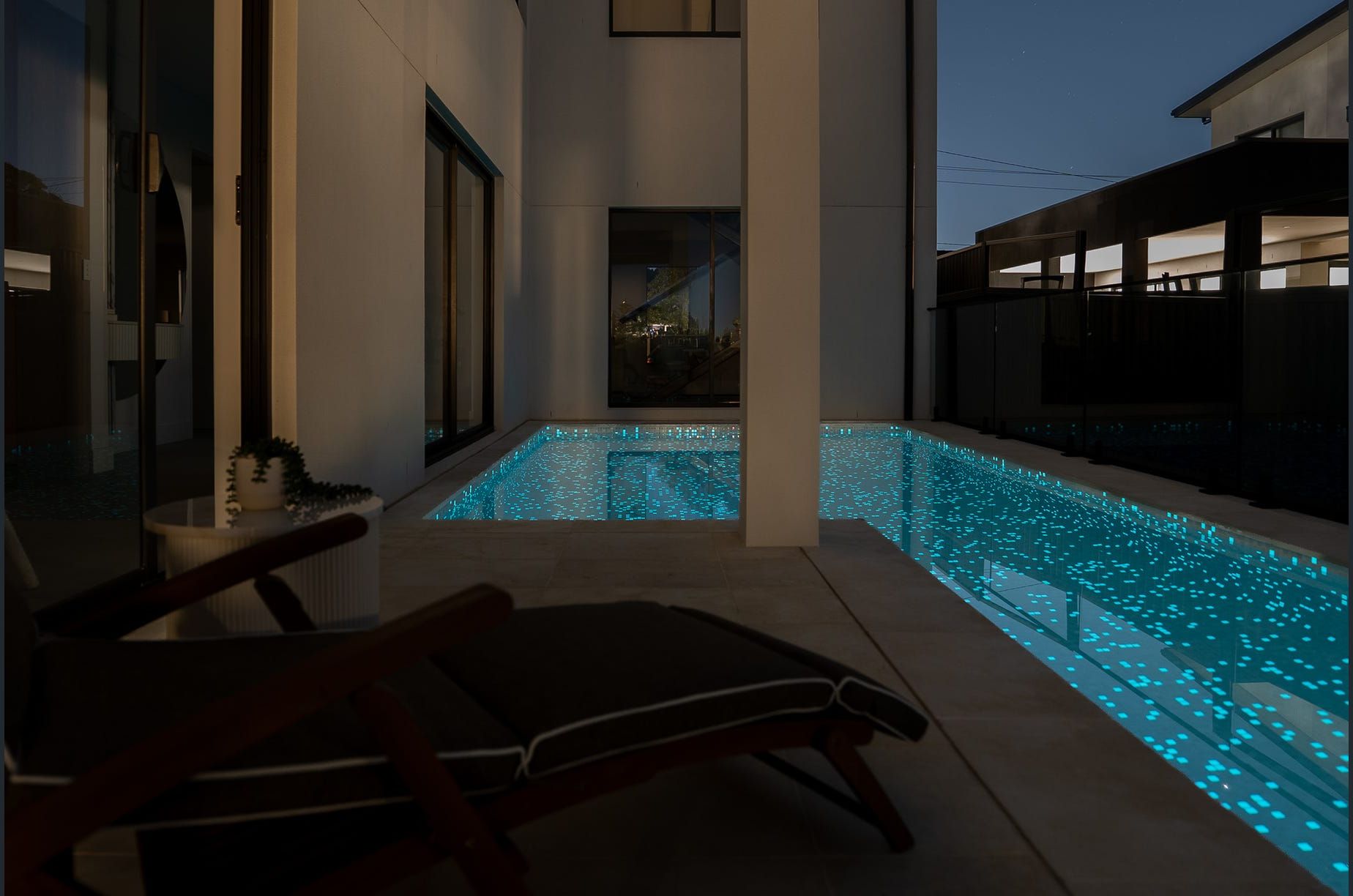 A modern outdoor pool area with a bench and a view of a building in the background.