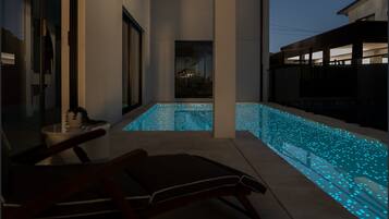 A modern outdoor pool area with a bench and a view of a building in the background.