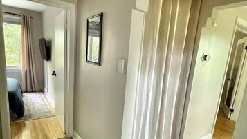 A hallway with a wooden floor, a door leading to a bedroom, and a staircase.