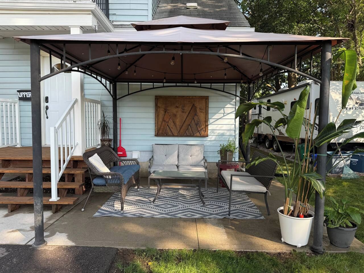 Ein überdachter Patio-Bereich mit einer Couch, Stühlen und einem Esstisch.