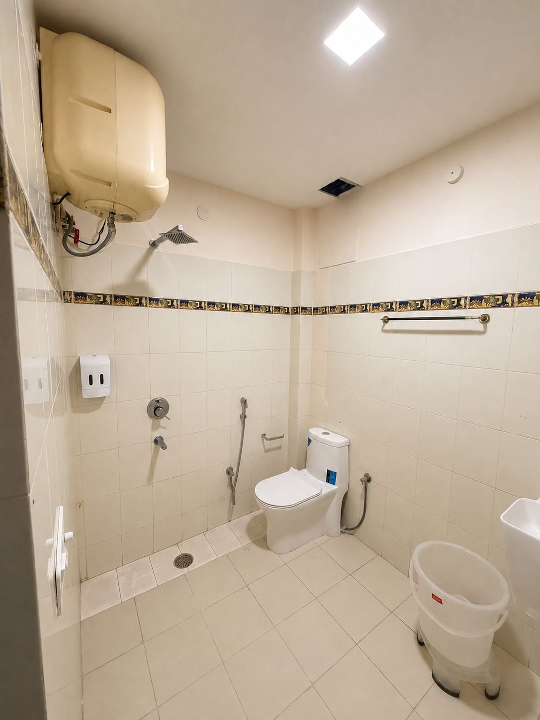 Un baño con inodoro, bidé, ducha y secamanos.