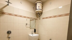 Et badeværelse med toilet, bidet, vask og brusebad.