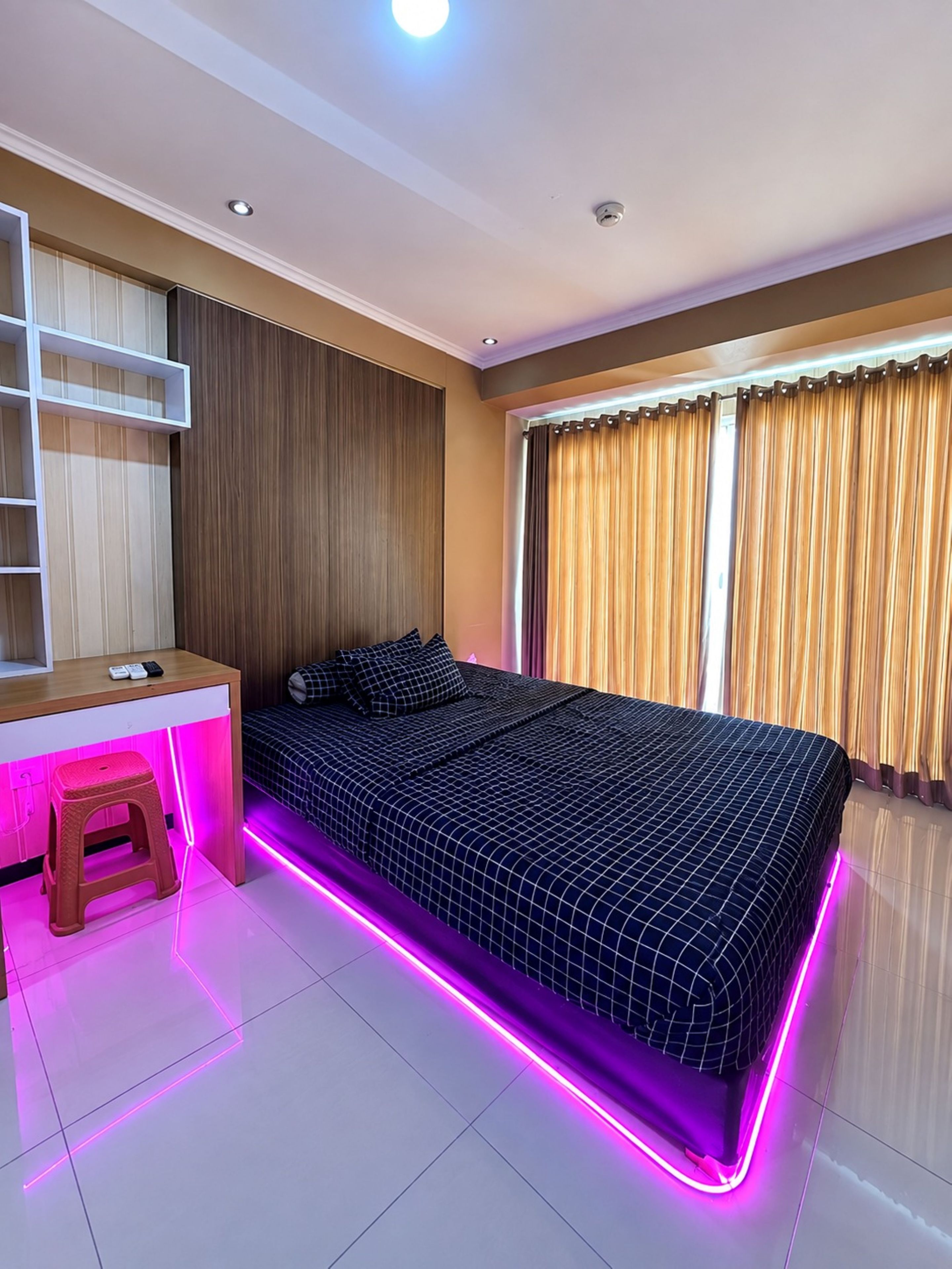 A bedroom with a bed, a desk, and a stool.