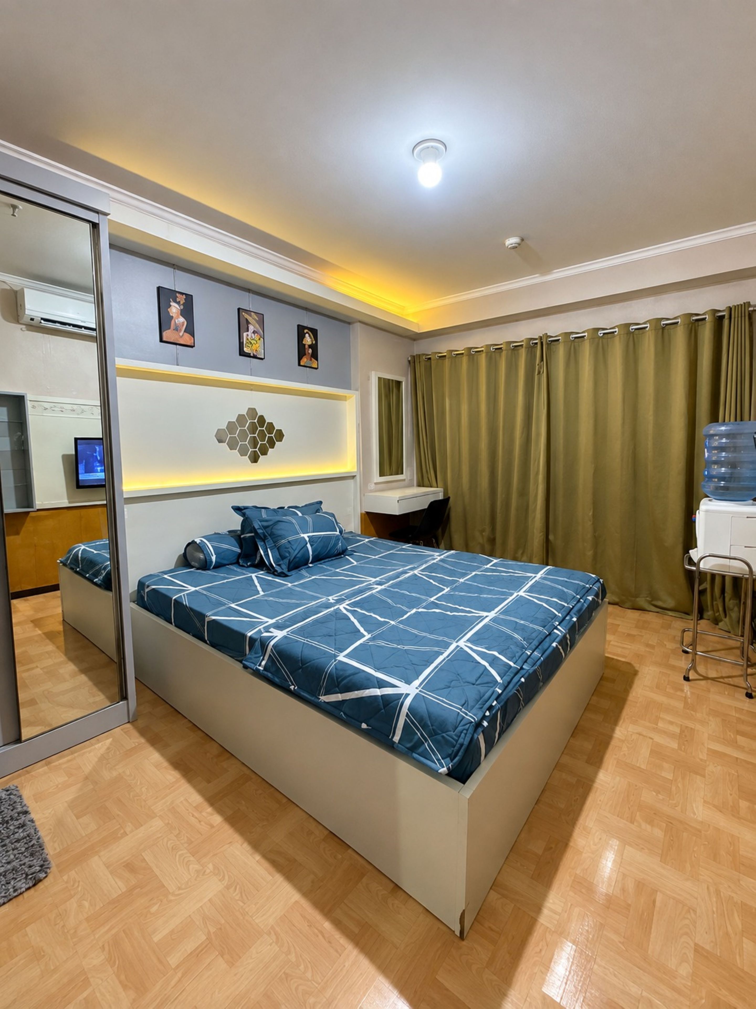 A modern bedroom with a large bed, a desk, and a mirror.