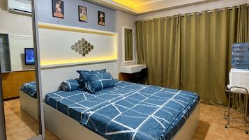 A modern bedroom with a large bed, a desk, and a mirror.
