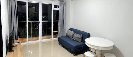 A modern living room with a sofa, a small round table, and a TV stand.
