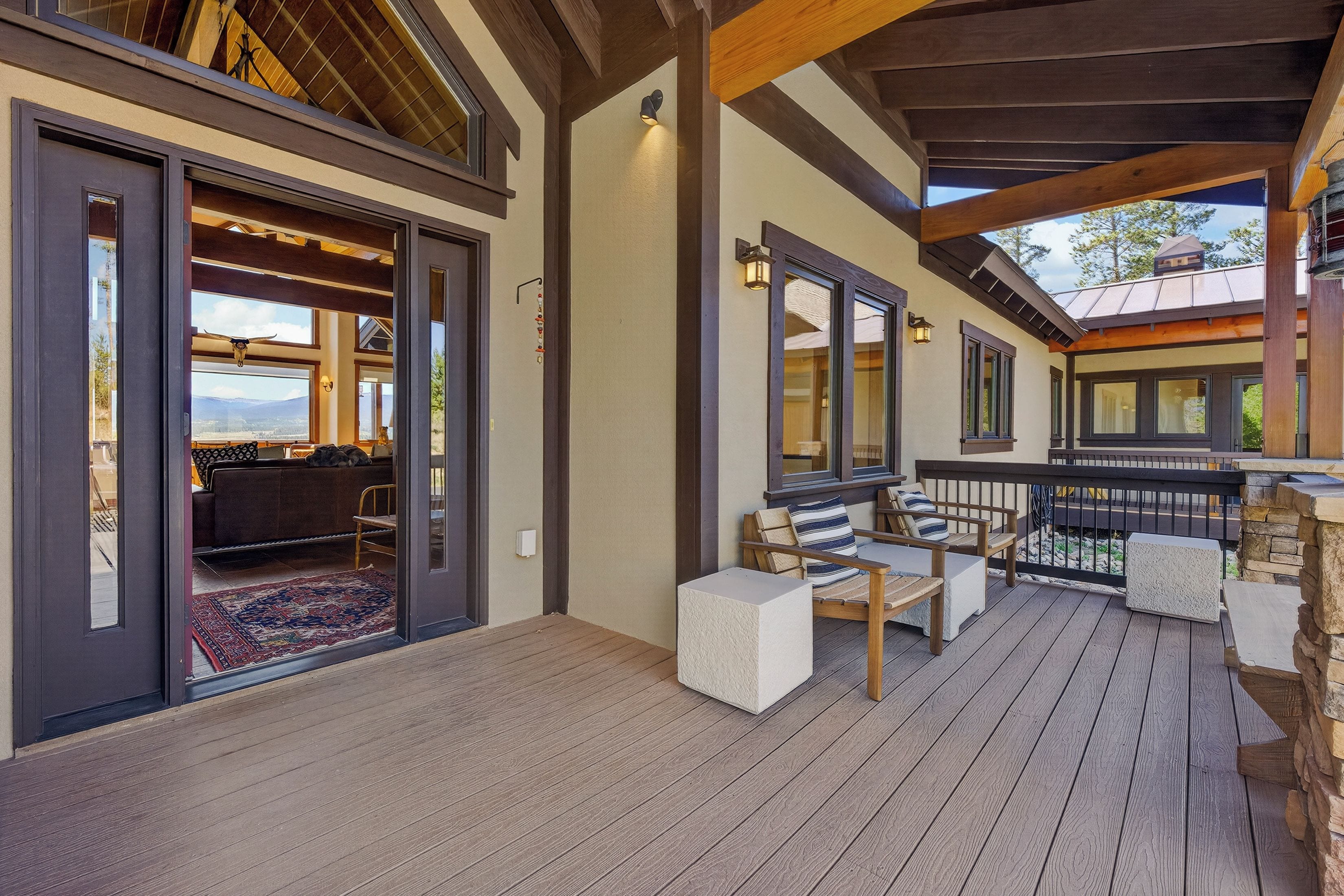 A covered outdoor area with a wooden deck, seating, and a view of the landscape.
