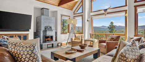 Amplia sala de estar con chimenea, asientos cómodos y ventanas grandes con vistas al exterior.