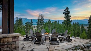 A stone patio with Adirondack chairs and a fire pit, overlooking a mountainous landscape. - 1459 GCR 5221 5 bedroom retreat, 10 private acres, outdoor hot tub, game room (Tabernash)