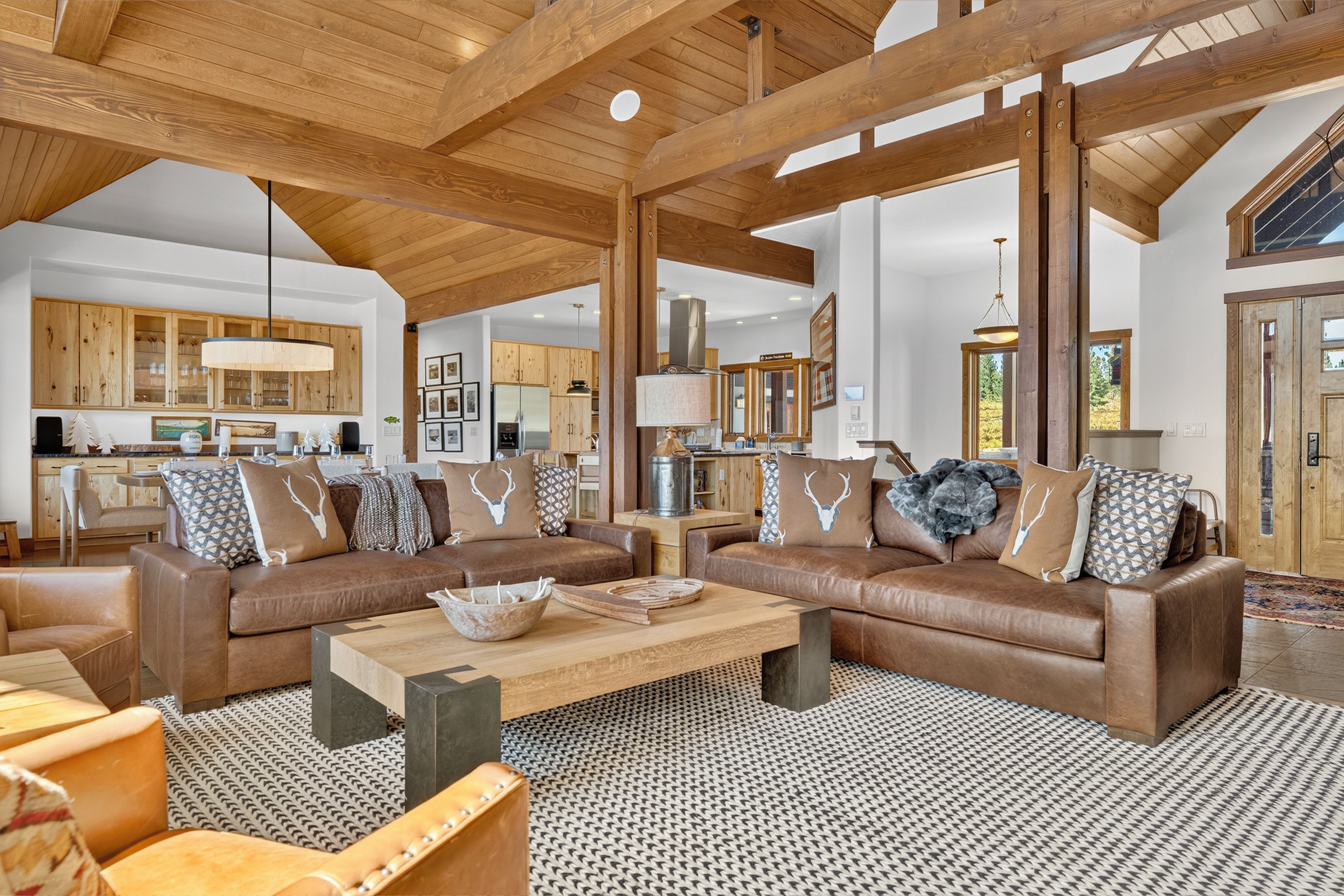 A spacious living area with a large brown leather sofa set, a coffee table, and a patterned rug.