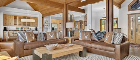A spacious living area with a large brown leather sofa set, a coffee table, and a patterned rug.
