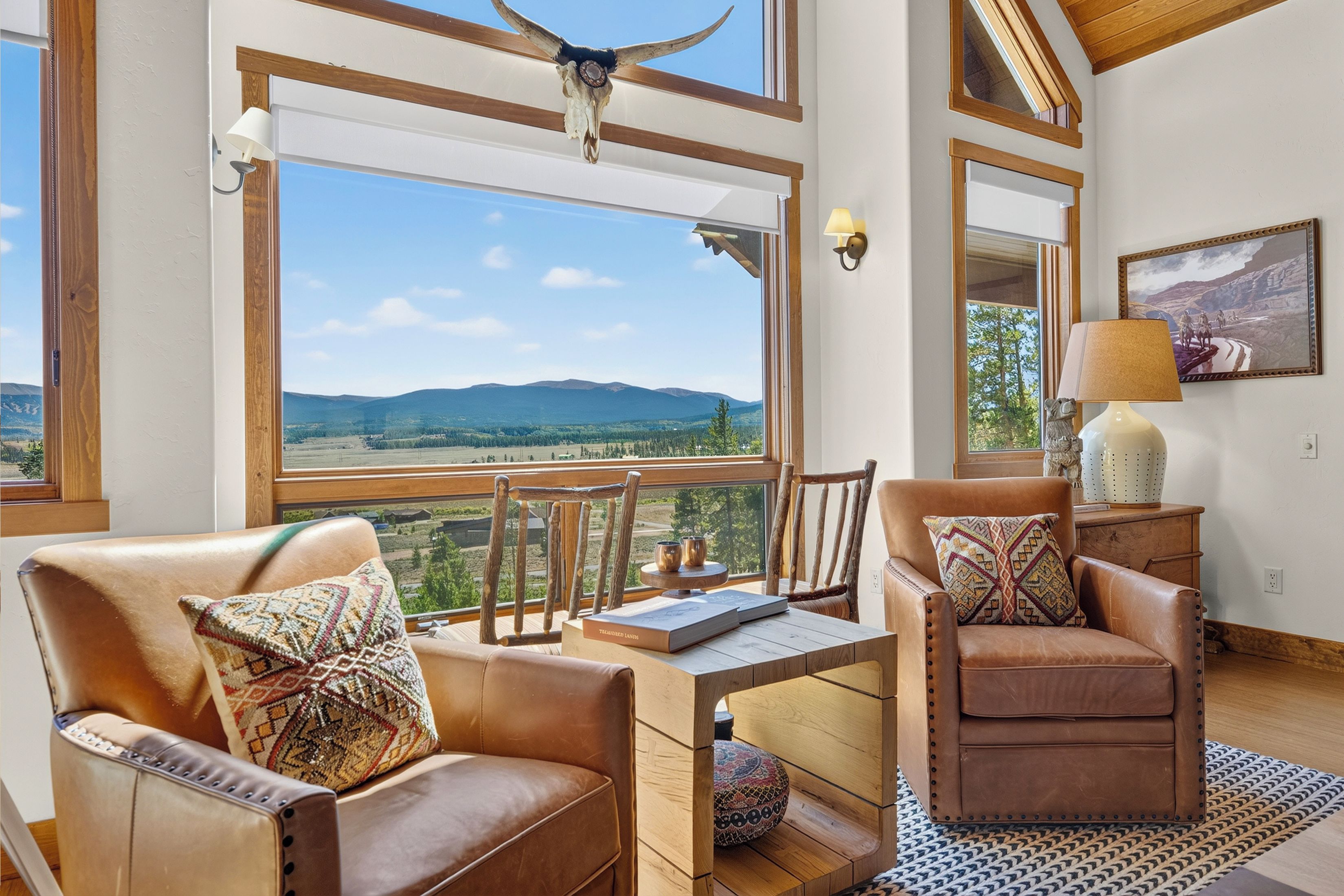 A spacious room with a large window offering a scenic view of mountains and a clear sky.